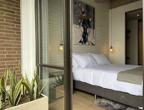 A modern bedroom with a bed, a glass partition, and a potted plant.