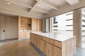 Een moderne keuken met houten kastjes, een centraal eiland en grote ramen met uitzicht op de stad.