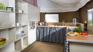 A compact kitchen with white shelves, a checkered tablecloth, and a window with a view. - Dog Friendly Safari Tent, Skylark at Sweffling Hall, Suffolk (Sweffling)