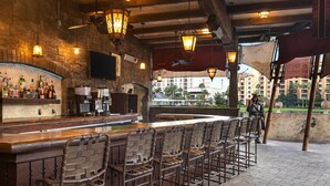 An outdoor bar area with brick walls, a wooden bar counter, and multiple bar stools.