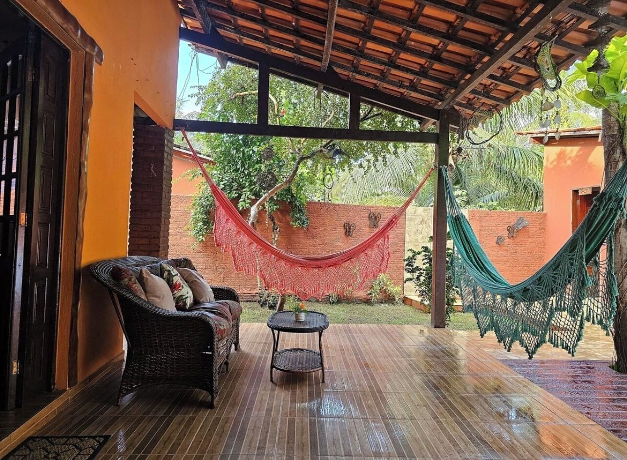 A covered patio with a wicker sofa, a small table, and two hammocks.
