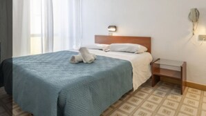 A hotel room with a bed, a bedside table, and a wall-mounted light fixture. - Hotel Criss (Rimini)