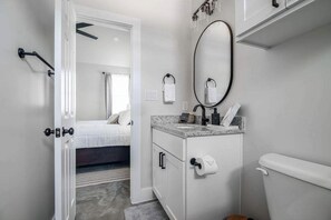 Une salle de bain moderne avec un meuble-lavabo blanc, un grand miroir et des toilettes.