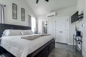 Une chambre à coucher avec un grand lit, un téléviseur fixé au mur et une armoire.