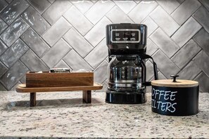 Eine Kaffeemaschine auf einer Küchenarbeitsplatte mit einem Behälter für Kaffeefilter, beschriftet mit 'COFFEE FILTERS'.