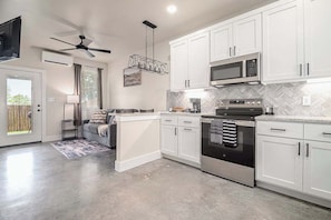 Una cocina moderna con gabinetes blancos, horno de acero inoxidable y microondas.