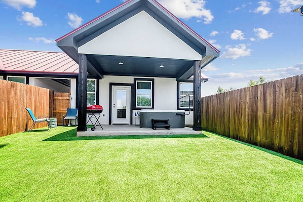A house with a covered patio, a barbecue grill, and a hot tub.