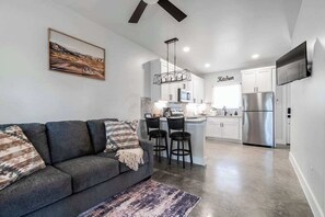 A modern kitchen with white cabinets, a stainless steel refrigerator, and a bar area.