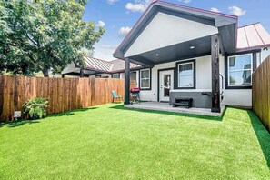 A modern house with a covered patio, a fenced backyard, and a well-maintained lawn.