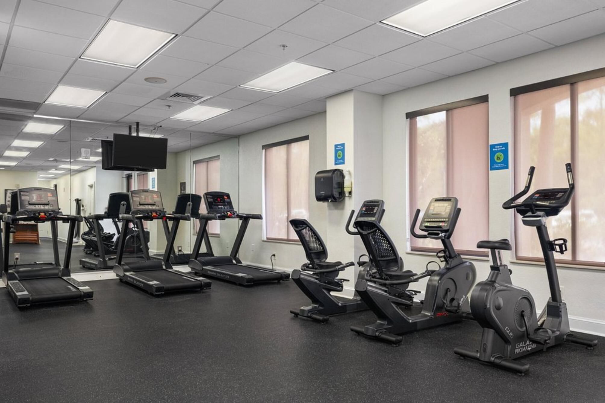 Un gimnasio con varias cintas de correr, elípticas y bicicletas estáticas.