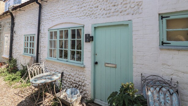 En hvid bygning med en struktureret facade, en grøn dør og et vindue med hvid ramme.