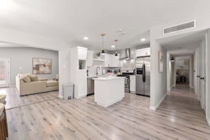 A modern kitchen with white cabinetry, a central island, and stainless steel appliances.