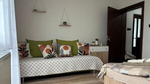 A bedroom with a bed, a bedside table, a nightstand, a hanging plant, and a door. - Villa White Stone - Zlatograd (ZLATOGRAD)
