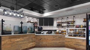 A modern kitchen with wooden accents, a coffee machine, and shelves with bottles. - 3BD/Orlando Near Disney - 5 Pools, Game Room, Café and Restaurant On-Site! (Lake Buena Vista)