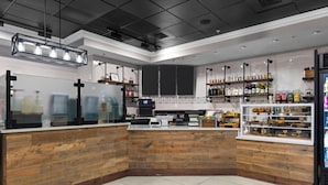 A modern kitchen with wooden accents, a coffee machine, and shelves with bottles. - 3BD/Orlando Near Disney - 5 Pools, Game Room, Café and Restaurant On-Site! (Lake Buena Vista)