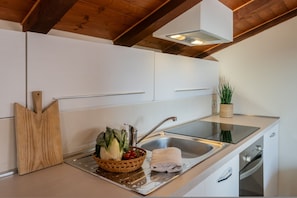 A modern kitchen with white cabinets, a stainless steel sink, and a wooden cutting board.