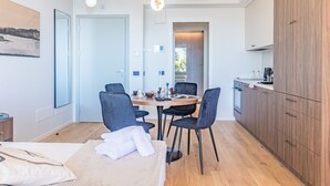 A modern hotel room with a bed, a dining table with chairs, a kitchen area, and a large window. - Aurora Apartment in Como (Como)