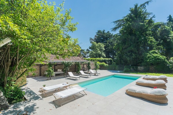 Ein Schwimmbecken mit Liegestühlen und einer Pergola.