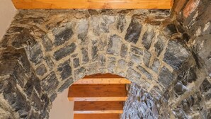 Un arco de piedra con escalones de madera que conducen a una viga de madera.