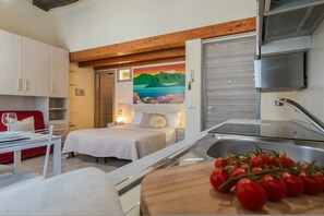 Une chambre d’hôtel de taille réduite comprenant un lit, un petit coin repas, une kitchenette et une salle de bain.