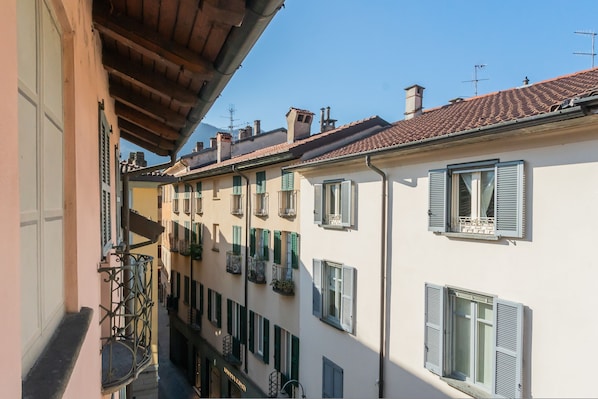 A narrow street with buildings featuring balconies and shutters.