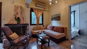 Una sala de estar con chimenea, un sofá, un sillón mecededor y una mesa de comedor.