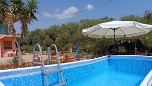 Una piscina con escalera, rodeada por una valla y una sombrilla.