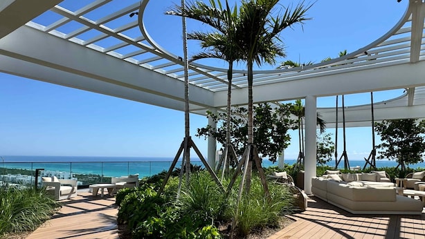 A covered outdoor area with a wooden deck, seating, and a view of the ocean. - Miami 72 Building - 360-degree Views - We host (Miami Beach)
