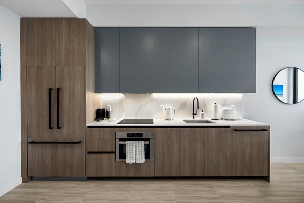 A modern kitchen with wooden cabinets, a built-in oven, and a stainless steel sink. - Miami 72 Building - 360-degree Views - We host (Miami Beach)