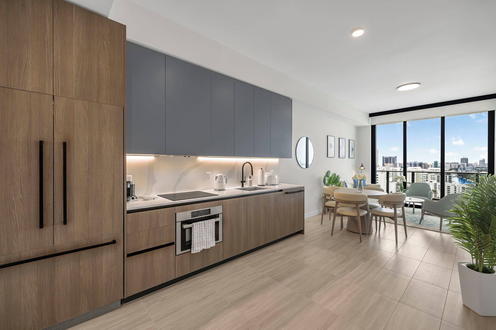A modern kitchen with wooden cabinets, a built-in oven, and a dining area with a view of the city.