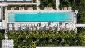 An aerial view of a resort with a large rectangular pool, sun loungers, and palm trees. - Miami 72 Building - 360-degree Views - We host (Miami Beach)