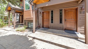 Una casa de madera con un porche cubierto, dos puertas y un letrero con el número 212.