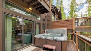Un jacuzzi en una terraza de madera con una puerta de vidrio que da a un patio.