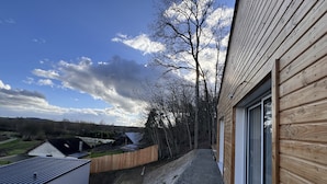 A residential area with a wooden house, a gravel path, and a view of the countryside.