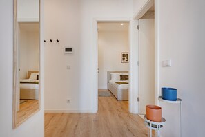 Un pasillo con una cama, una mesita de noche y un pequeño estante con dos recipientes.