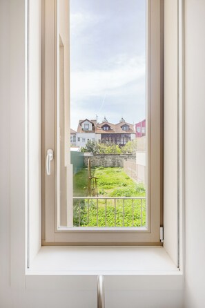 Una ventana con vista a un jardín y casas.