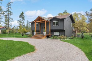 Une maison à deux étages avec un porche couvert, une allée en gravier et une pelouse bien entretenue.