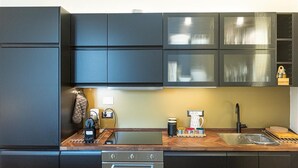 A modern kitchen with dark cabinetry, a wooden countertop, a built-in oven, and a stainless steel sink. - Casa Prati apartment (Rome)