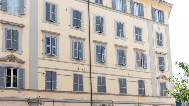 A multi-story building with evenly spaced windows and shutters, featuring a symmetrical facade and a balcony on the upper floor. - Casa Prati apartment (Rome)