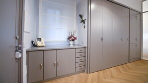 A room with a large wardrobe, a small desk with a telephone, and a window with a view.