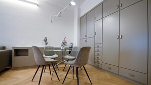A modern dining area with a glass table, grey upholstered chairs, and a grey wardrobe with multiple compartments.