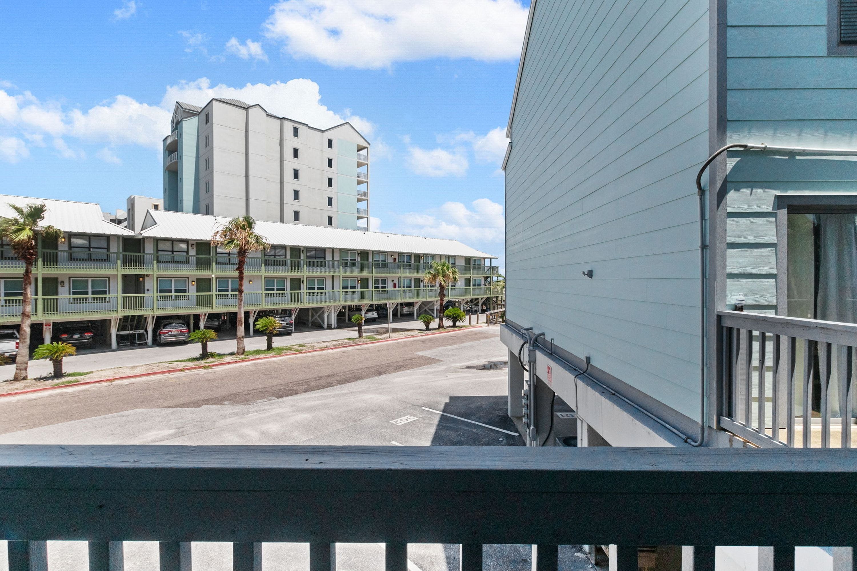 A hotel with a multi-story structure, a parking lot, and a clear sky.