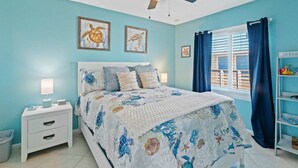 A bedroom with a bed, nightstands, a ceiling fan, and artwork on the walls. - 2BR Retreat With Pool Near Beach and The Hangout (Gulf Shores)