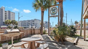A patio area with a round table and benches, a grill, and a sign for Gulf View Condominium. - 2BR Retreat With Pool Near Beach and The Hangout (Gulf Shores)