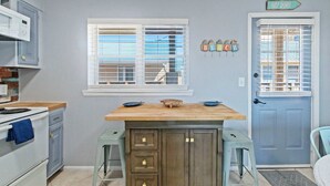 A kitchen with a wooden island, white cabinets, and a blue door. - Three 2br Condos Walk to Beach Hangout (Gulf Shores)