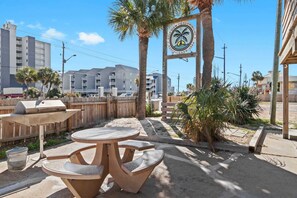 Eine Terrasse mit rundem Tisch und Bänken, einem Grill und einem Schild für das Gulf View Condominium.