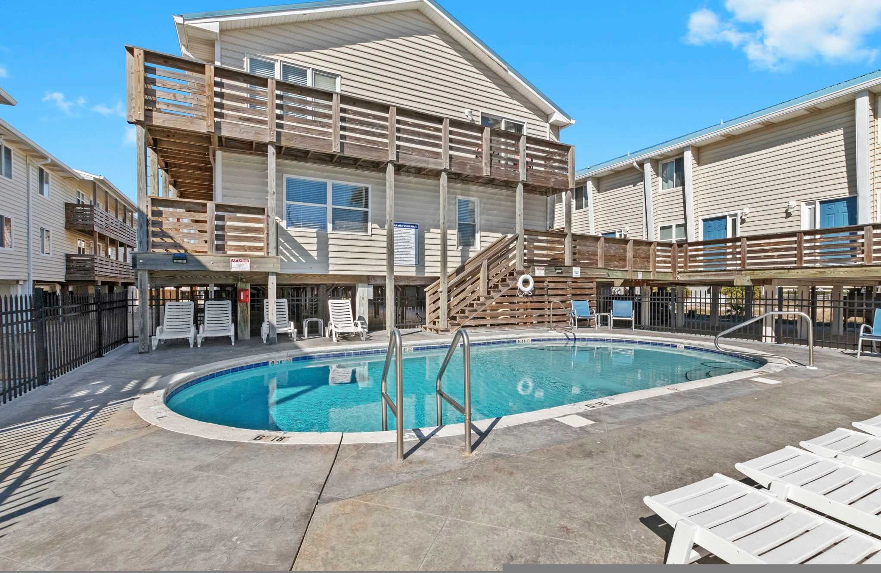 A hotel with a pool area, including a wooden deck and lounge chairs.