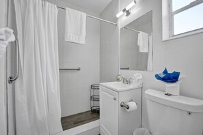 A bathroom with a shower, toilet, sink, and mirror. - Waves on Desoto Studio With Pool 3 (Hollywood)