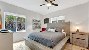 A modern bedroom with a large bed, a ceiling fan, and a nightstand with a lamp. - Daddy House-victoria Park With Pool (Fort Lauderdale)