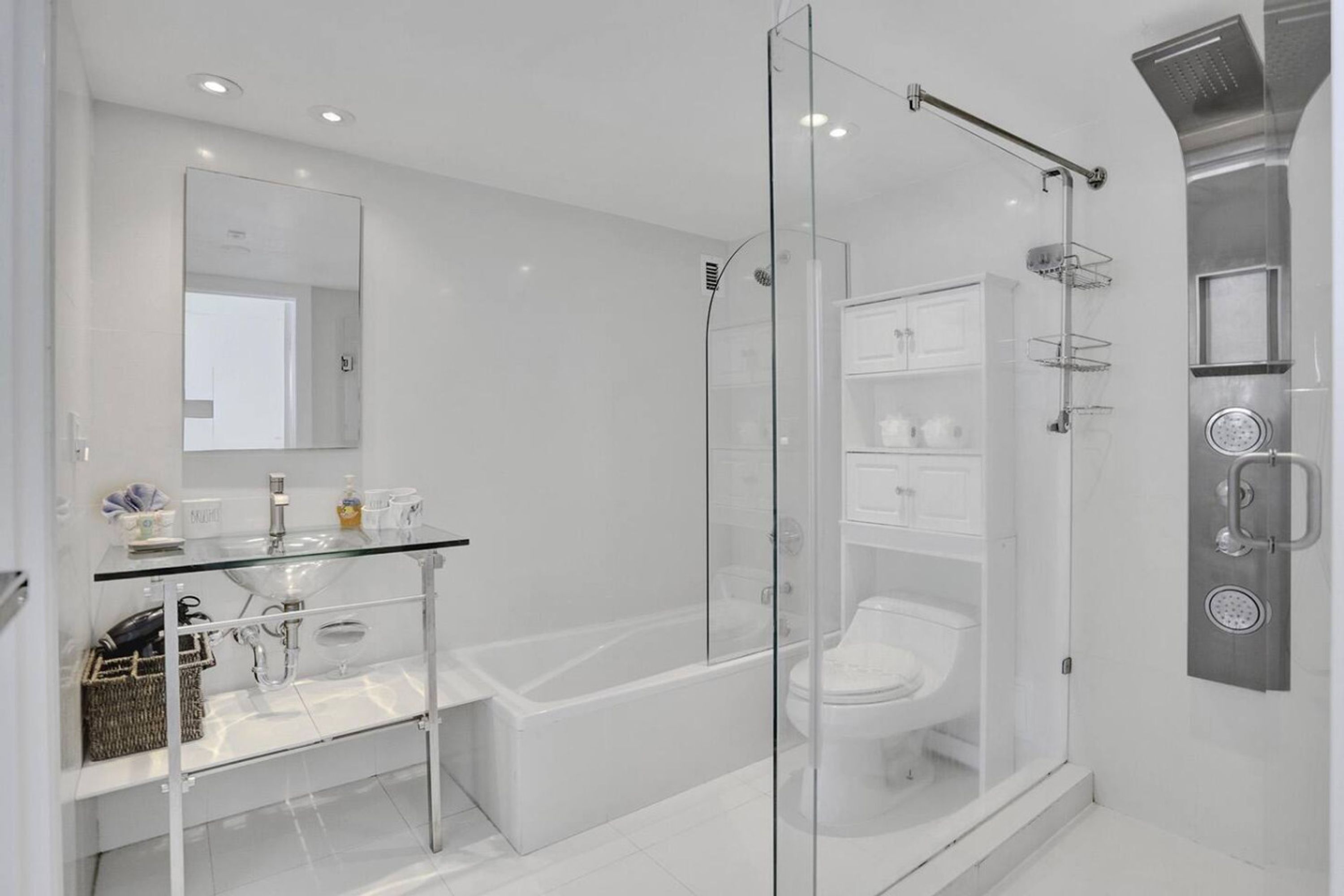A modern bathroom with a glass-enclosed shower, a glass sink, and a white bathtub.